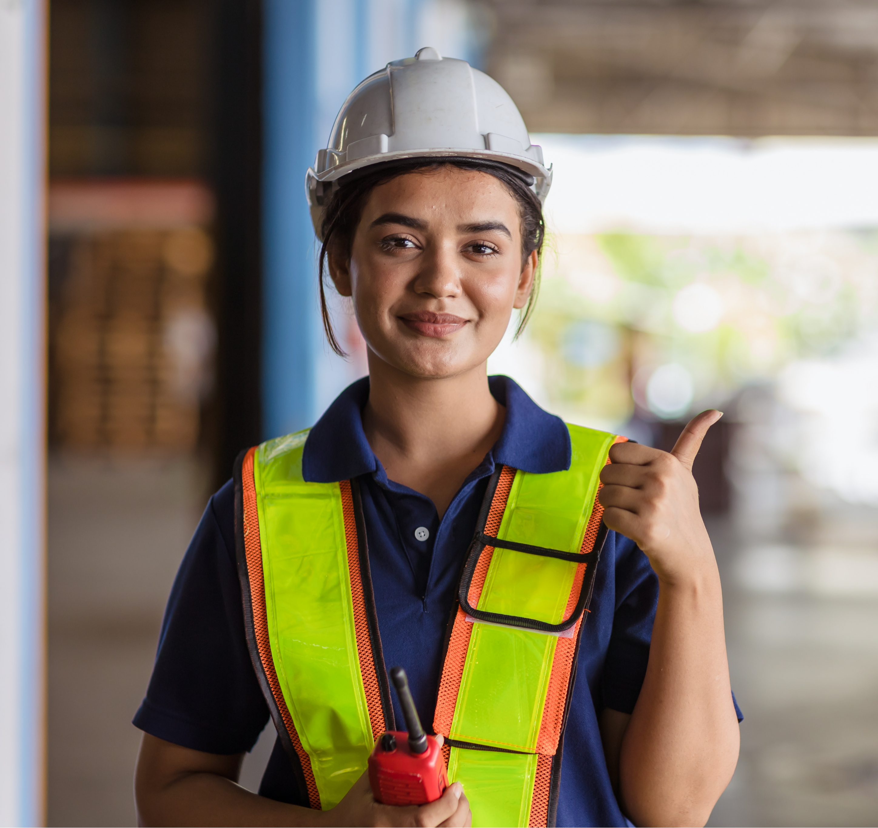 Trabajadora con casco y chaleco de seguridad industrial.