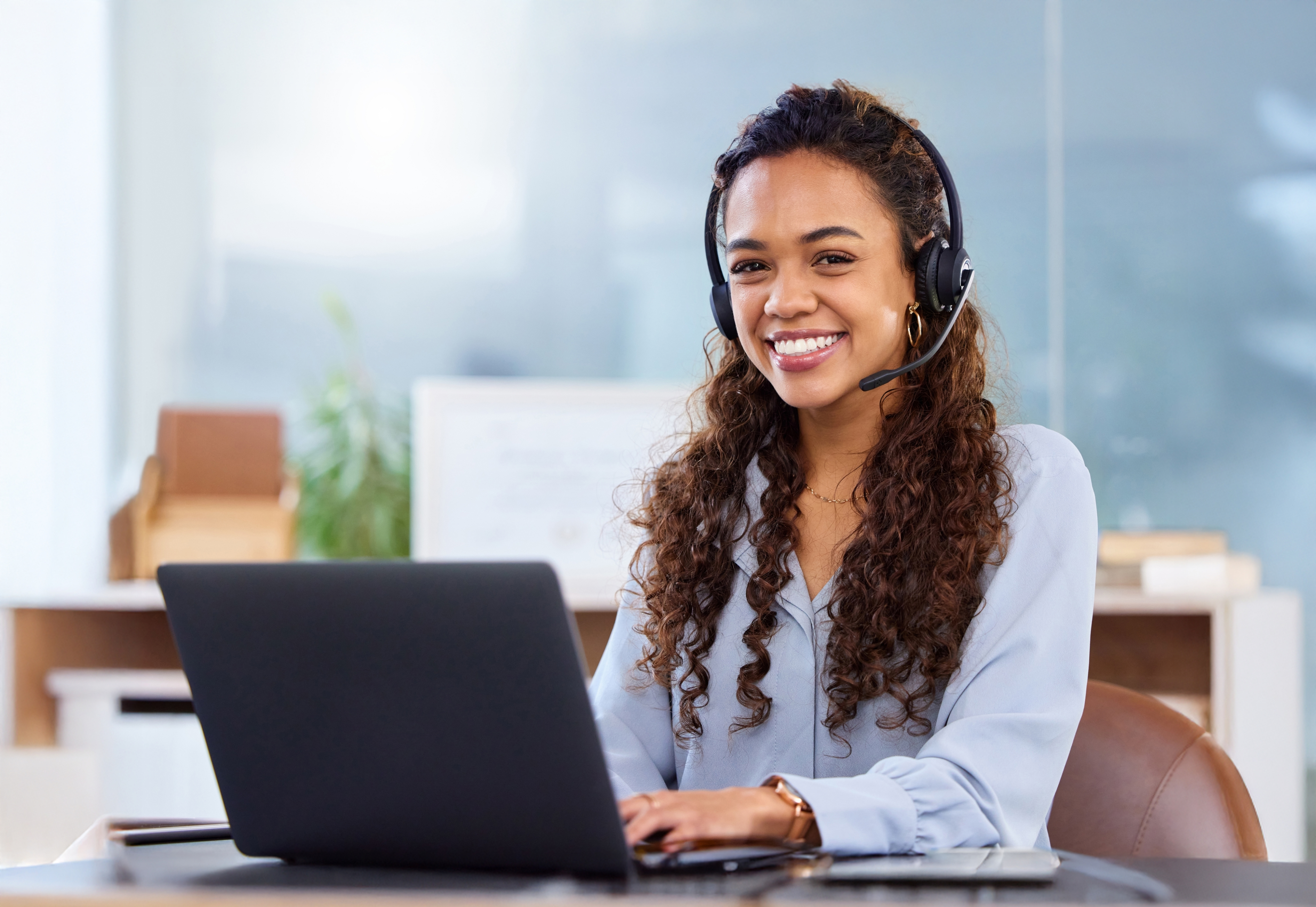 Asesora de servicio al cliente con audífonos trabajando en portátil.